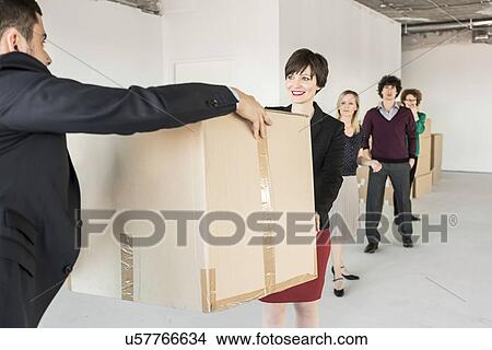 Picture - Businesspeople moving cardboard boxes around unfinished office interior. Fotosearch