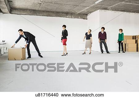 Stock Image - Businesspeople moving cardboard boxes around unfinished office interior. Fotosearch