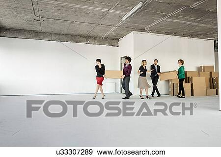Businesspeople moving cardboard boxes around unfinished office interior View Large Photo Image Stock Photo - Businesspeople moving cardboard boxes around unfinished office interior. Fotosearch