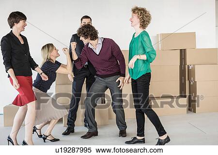 Stock Photography - Businesspeople playing around in front of pile of cardboard boxes. Fotosearch