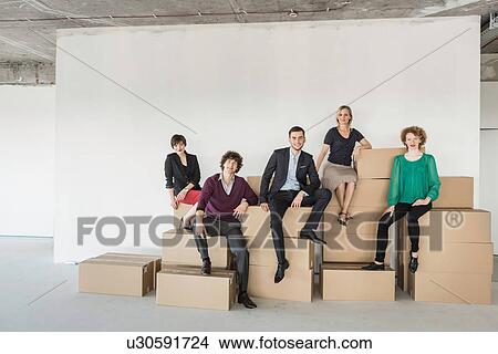 Picture - Businesspeople sitting on pile of cardboard boxes. Fotosearch