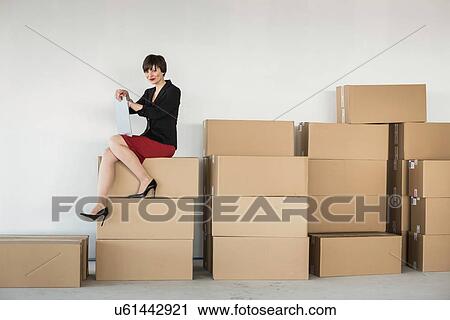 Businesswoman sitting on stack of cardboard boxes View Large Photo Image Stock Image - Businesswoman sitting on stack of cardboard boxes. Fotosearch