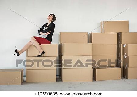 Businesswoman sitting on stack of cardboard boxes View Large Photo Image Stock Photography - Businesswoman sitting on stack of cardboard boxes. Fotosearch