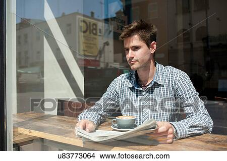 Candid portrait of young man looking out of cafe window View Large Photo Image Picture - Candid portrait of young man looking out of cafe window. Fotosearch