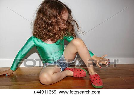 Stock Photo - Child on floor looking at finger nails. Fotosearch