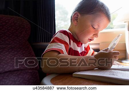 Close up of young boy with puzzle book on train View Large Photo Image Stock Photo - Close up of young boy with puzzle book on train. Fotosearch