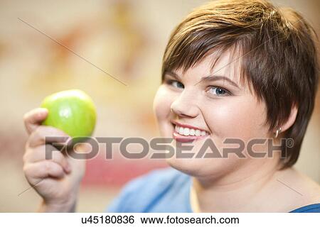 Stock Photograph - Close up portrait of young woman holding apple. Fotosearch