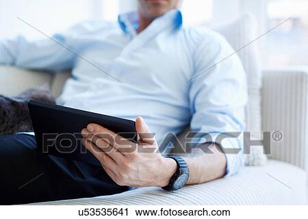 Stock Image - Cropped shot of man's midsection holding digital tablet. Fotosearch