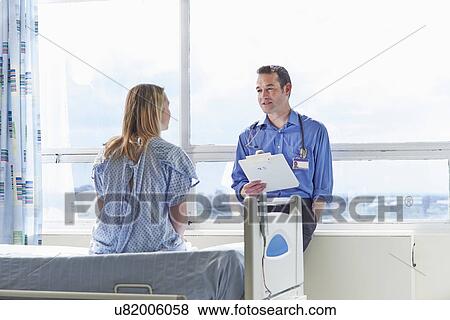 Doctor talking to patient sitting on hospital bed View Large Photo Image Stock Photo - Doctor talking to patient sitting on hospital bed. Fotosearch