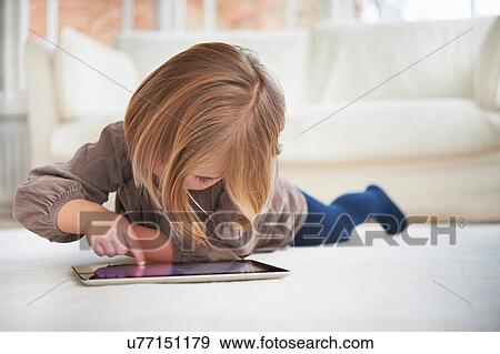 Girl lying on floor using digital tablet View Large Photo Image Stock Photo - Girl lying on floor using digital tablet. Fotosearch