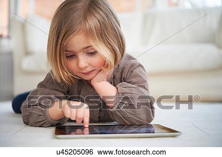 Girl lying on floor using digital tablet View Large Photo Image Stock Photograph - Girl lying on floor using digital tablet. Fotosearch