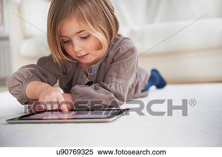 Stock Photography - Girl lying on floor using digital tablet. Fotosearch