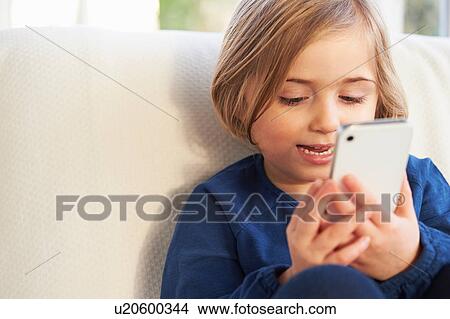 Girl on sofa using smartphone View Large Photo Image Picture - Girl on sofa using smartphone. Fotosearch