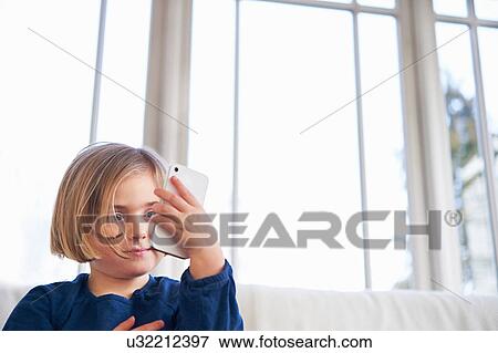 Girl on sofa using smartphone View Large Photo Image Stock Photo - Girl on sofa using smartphone. Fotosearch