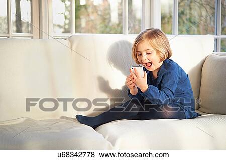 Stock Photo - Girl on sofa using smartphone. Fotosearch
