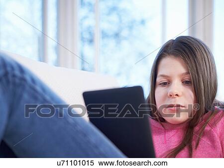 Girl using digital tablet on sofa View Large Photo Image Stock Photography - Girl using digital tablet on sofa. Fotosearch