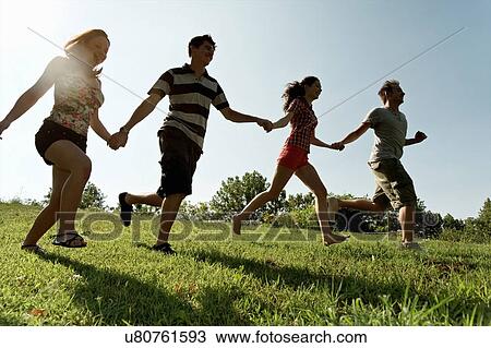Group of young adults holding hands and running View Large Photo Image Stock Image - Group of young adults holding hands and running. Fotosearch