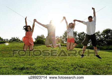 Group of young adults jumping mid air in field View Large Photo Image Picture - Group of young adults jumping mid air in field. Fotosearch