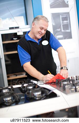 Stock Image - Kitchen appliance salesman in showroom. Fotosearch