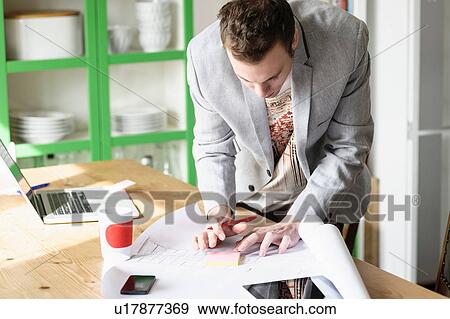 Man bending over work documents View Large Photo Image Stock Photo - Man bending over work documents. Fotosearch