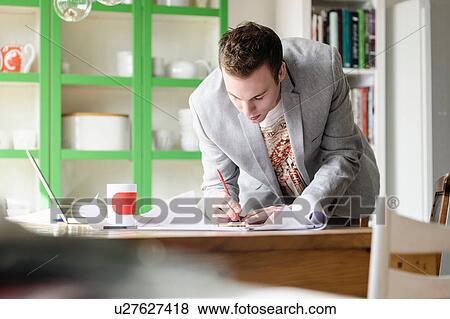 Stock Photo - Man bending over work documents. Fotosearch