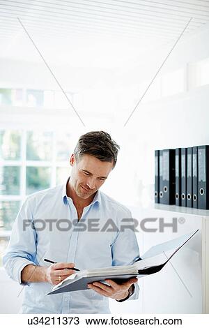 Man looking at folder of paperwork View Large Photo Image Stock Image - Man looking at folder of paperwork. Fotosearch