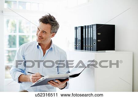 Stock Image - Man looking at folder of paperwork. Fotosearch