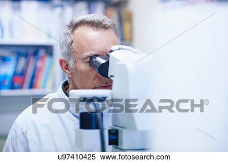 Man looking through microscope View Large Photo Image Stock Photography - Man looking through microscope. Fotosearch