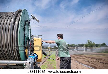 Stock Photography - Man operating irrigation system. Fotosearch
