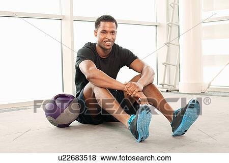 Man sitting on floor in gymnasium View Large Photo Image Stock Photo - Man sitting on floor in gymnasium. Fotosearch