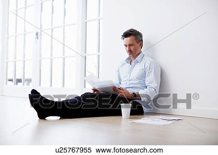 Man sitting on floor looking at paperwork View Large Photo Image Stock Photography - Man sitting on floor looking at paperwork. Fotosearch
