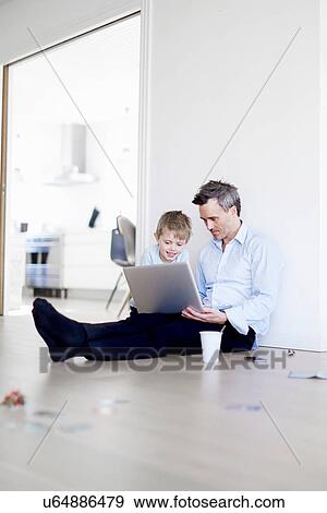 Man sitting on floor using laptop, son watching View Large Photo Image Stock Photo - Man sitting on floor using laptop, son watching. Fotosearch