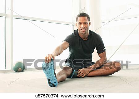 Man sitting touching toes stretching View Large Photo Image Picture - Man sitting touching toes stretching. Fotosearch