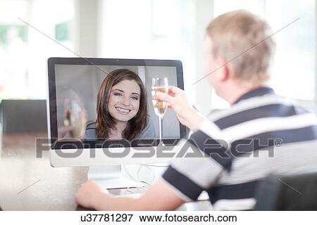 Man toasting wife using video call View Large Photo Image Stock Photo - Man toasting wife using video call. Fotosearch