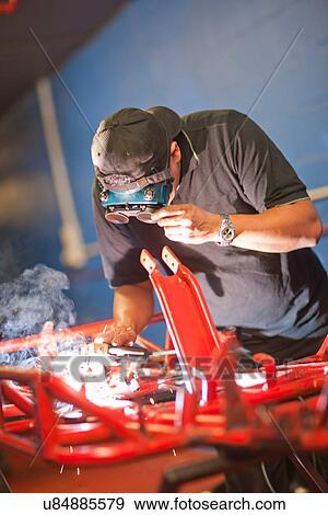 Stock Photo - Mechanic welding go cart. Fotosearch