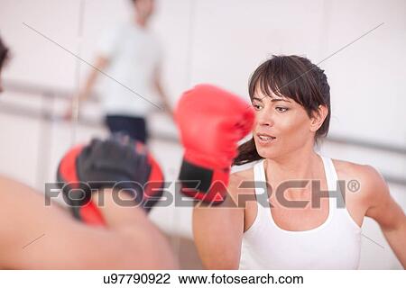 Stock Image - Mid adult woman with personal trainer. Fotosearch