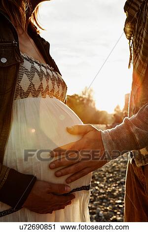 Midsection of pregnant woman and partner touching bump View Large Photo Image Stock Image - Midsection of pregnant woman and partner touching bump. Fotosearch