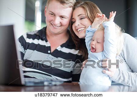 Stock Photo - Mother and father with baby boy using computer. Fotosearch