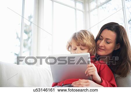 Mother and son on sofa using digital tablet View Large Photo Image Stock Image - Mother and son on sofa using digital tablet. Fotosearch