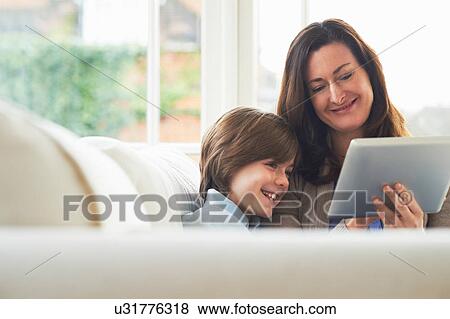 Stock Photo - Mother and son on sofa using digital tablet. Fotosearch