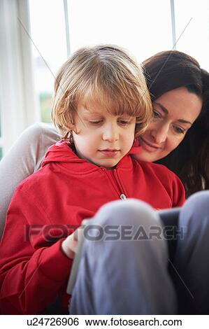 Stock Photograph - Mother and son on sofa using digital tablet. Fotosearch