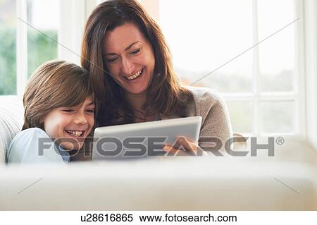 Mother and son on sofa using digital tablet View Large Photo Image Stock Photography - Mother and son on sofa using digital tablet. Fotosearch