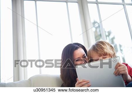 Mother and son on sofa using digital tablet View Large Photo Image Stock Photography - Mother and son on sofa using digital tablet. Fotosearch