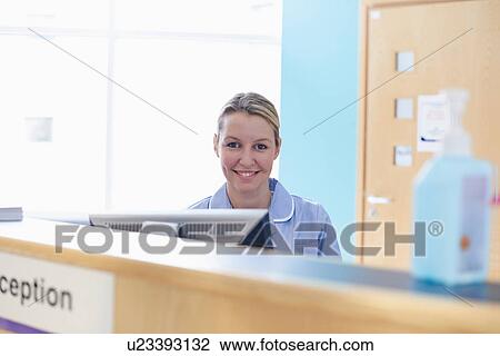 Stock Image - Nurse sitting at reception desk. Fotosearch
