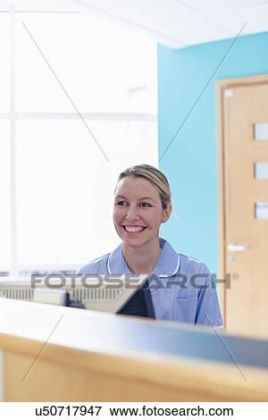 Stock Photo - Nurse sitting at reception desk. Fotosearch