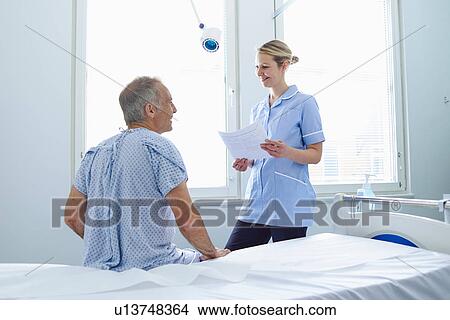Nurse standing talking to patient sitting on hospital bed View Large Photo Image Picture - Nurse standing talking to patient sitting on hospital bed. Fotosearch