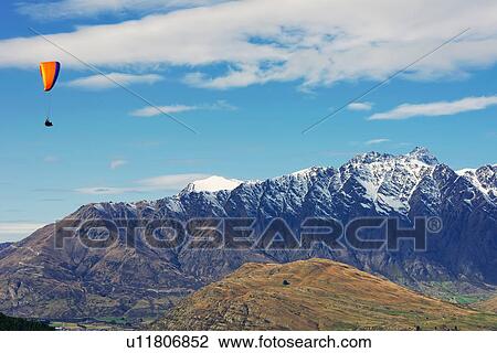 Stock Image - Paragliding over Remarkables Mountain Range, Queenstown, South Island, New Zealand. Fotosearch