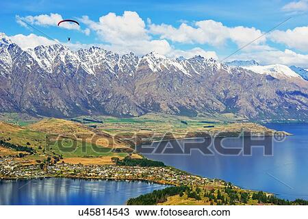 Stock Image - Paragliding over Remarkables Mountain Range, Queenstown, South Island, New Zealand. Fotosearch