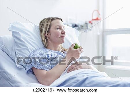 Stock Photo - Patient lying in hospital bed eating apple. Fotosearch
