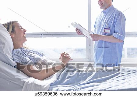 Patient lying in hospital bed laughing with nurse View Large Photo Image Stock Photograph - Patient lying in hospital bed laughing with nurse. Fotosearch